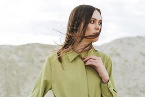 mode schoonheid portret van jong vrouw met lang haar- in groen biologisch overhemd Aan woestijn achtergrond foto