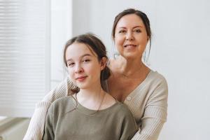 aantrekkelijk moeder midden- leeftijd vrouw en dochter tiener samen in de licht interieur foto