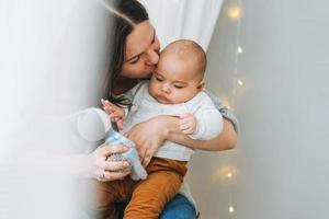 jong moeder spelen met schattig baby jongen in helder slaapkamer, natuurlijk tonen, liefde emotie foto