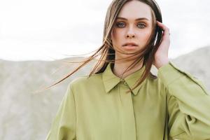mode schoonheid portret van jong vrouw met lang haar- in groen biologisch overhemd Aan woestijn achtergrond foto