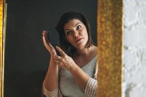 mooi glimlachen jong vrouw plus grootte lichaam positief in huis kleren poetsen haar- in de badkamer, schoonheid ochtend- routine- foto