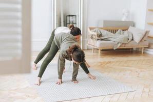 aantrekkelijk moeder midden- leeftijd vrouw en dochter tiener ptactiek yoga samen in de helder kamer foto