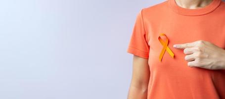 oranje lint voor leukemie, nierkankerdag, wereld multiple sclerose, crps, zelfverwondingsmaand. gezondheidszorg en woord kanker dag concept foto