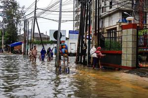 semarang, december 2022. meerdere mensen zijn draag- zakken gevulde met voedsel en kleding naar bereiden voor evacuatie na hun huis was overstroomd foto