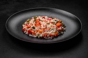 heerlijk vers risotto met groenten, specerijen en kruiden Aan een zwart bord foto
