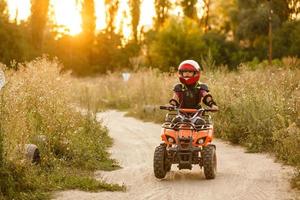 de weinig meisje ritten een quad fiets atv. een mini quad fiets is een koel meisje in een helm en beschermend kleding. elektrisch quad fiets elektrisch auto voor kinderen populariseert groen technologie. foto