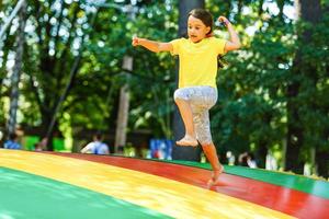 gelukkig weinig meisje hebben pret terwijl jumping Aan trampoline foto