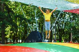 weinig kind jumping Aan groot trampoline - buitenshuis in achtertuin foto