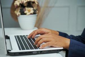 afbeelding van een Aziatisch bedrijf Mens handen werken in kantoor met laptop computer, typen Aan toetsenbord Bij zijn bureau, dichtbij omhoog foto