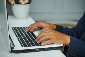 afbeelding van een Aziatisch bedrijf Mens handen werken in kantoor met laptop computer, typen Aan toetsenbord Bij zijn bureau, dichtbij omhoog foto