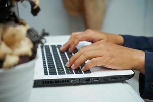 afbeelding van een Aziatisch bedrijf Mens handen werken in kantoor met laptop computer, typen Aan toetsenbord Bij zijn bureau, dichtbij omhoog foto