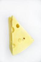 een groot stuk van kaas Aan een wit achtergrond. een driehoekig stuk van kaas met gaten. foto