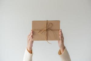 vrouw handen Holding Cadeau doos met een lint boog. minimalistische concept van geven een Geschenk. foto