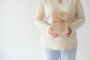 vrouw handen Holding Cadeau doos met een lint boog. minimalistische concept van geven een Geschenk. foto