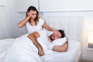 paar in bed, Mens snurken en vrouw kan niet slaap. snurken Mens en jong vrouw. paar slapen in bed. jong meisje kan niet slaap omdat van haar man's snurken Holding zijn neus. snurken Mens probleem foto