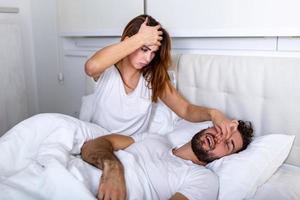 paar in bed, Mens snurken en vrouw kan niet slaap. snurken Mens en jong vrouw. paar slapen in bed. jong meisje kan niet slaap omdat van haar man's snurken Holding zijn neus. snurken Mens probleem foto