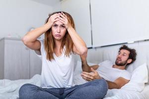 paar met problemen hebben onenigheid in bed. gefrustreerd paar ruzie maken en hebben huwelijk problemen, jong paar in een argument Aan bed in slaapkamer foto