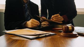 zaken en advocaten bespreken contractpapieren met koperen schaal op bureau in kantoor. wet, juridische diensten, advies, rechtvaardigheid en wet concept foto met film grain effect