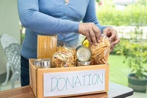 vrijwilligers die verschillende soorten droog voedsel in de donatiebox stoppen om mensen te helpen. foto