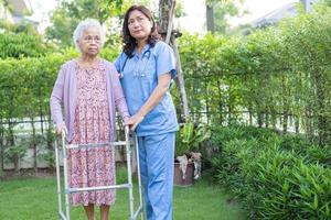 dokter helpt en verzorgt aziatische senior of oudere oude dame vrouw gebruikt rollator met een sterke gezondheid tijdens het wandelen in het park in een fijne frisse vakantie. foto