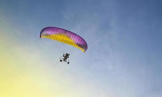 paraglider met een motor vliegt in de blauw lucht foto