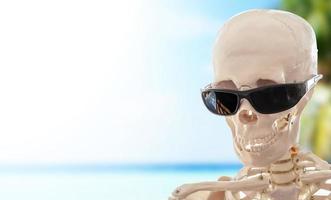 menselijk skelet met bril op een tropisch strand foto