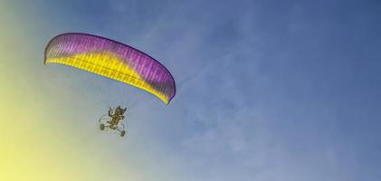 paraglider met een motor vliegt in de blauw lucht foto