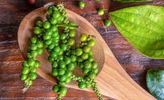 top visie van groen een bundel van vers peperkorrels of specerijen voor Koken in een houten lepel foto