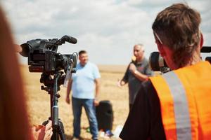 pidhaitsi, Oekraïne - juli 20, 2019 Mens staat in de landbouwkundig veld- en pratend in de microfoon. camera's in voorkant van hem foto
