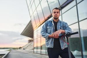 modieus Mens staand tegen modern bedrijf gebouw foto