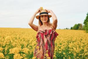 zwanger vrouw poseren Aan een veld- van geel bloemen foto