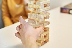 familie Speel bord spel. handen nemen houten blok van toren. foto