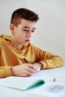tiener- jongen schrijven huiswerk Bij huis. onderwijs concept foto