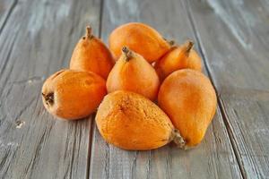 mispel rijp, loquats fruit groep van Japans oranje fruit mispels, exotisch, sappig zoet pruimen Aan houten achtergrond foto