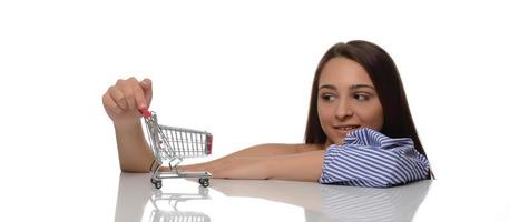 vrouw gedachte over winkelen. meisje is denken over winkelen. vrouw kiest waar naar maken aankoop. vrouw klant met mini trolley van supermarkt. foto