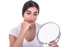 vrouw controle haar gezicht huid in voorkant van een spiegel foto