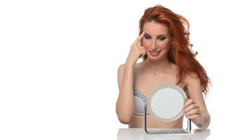 vrouw controle haar gezicht huid in voorkant van een spiegel foto