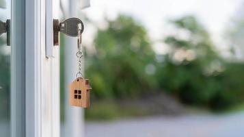 landheer sleutel voor ontgrendelen huis is aangesloten in de deur. tweede hand- huis voor huur en uitverkoop. sleutelhanger is blazen in de wind. hypotheek voor nieuw huis, kopen, verkopen, renoveren, investering, baasje, landgoed foto