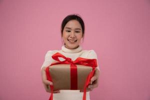 viering vakantie, presenteert. jong Aziatisch vrouw gelukkig en glimlach houden geschenk dozen in partij voor vieren verjaardag Aan roze achtergrond, genieten vrouw te ontvangen nieuw jaar geschenk, Kerstmis dag, Valentijn dag. foto