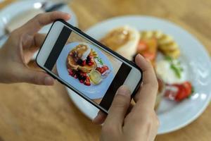 vrouw nemen afbeelding van een maaltijd Aan de tafel na bestellen voedsel online naar eten Bij huis. fotografie en gebruik telefoon concepten foto