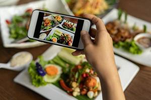 vrouw nemen afbeelding van een maaltijd Aan de tafel na bestellen voedsel online naar eten Bij huis. fotografie en gebruik telefoon concepten foto