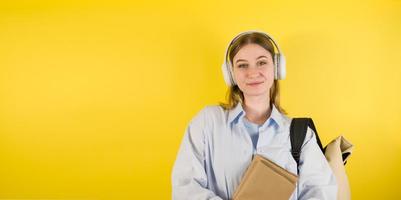 glimlachen Kaukasisch jong vrouw luisteren naar de podcast of muziek- in de hoofdtelefoons en houdt boeken. onderwijs conceptbanner met plaats voor sms terug naar school- Universiteit foto