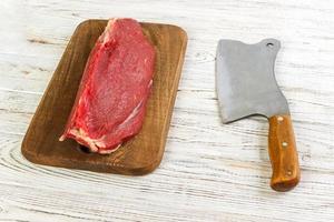 rauw rundvlees vlees Aan snijdend bord met oud wijnoogst hakmes foto