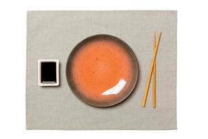 leeg ronde bruin bord met eetstokjes voor sushi en soja saus Aan grijs servet achtergrond. top visie met kopiëren ruimte voor u ontwerp foto