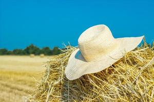 een eenzaam boer hoed Aan een hooiberg in de veld- na een moeilijk werk foto