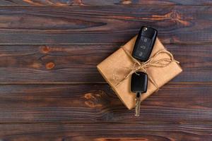 zwart auto sleutel in een Cadeau doos Aan houten tafel foto