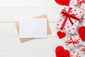 envelop mail met rood hart en geschenk doos over- wit houten achtergrond. Valentijn dag kaart, liefde of bruiloft groet concept foto