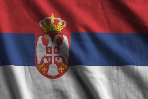 Servië vlag met groot vouwen golvend dichtbij omhoog onder de studio licht binnenshuis. de officieel symbolen en kleuren in banier foto
