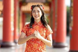 Aziatisch vrouw in rood cheongsam qipao jurk is betalen respect en dankbaarheid binnen Chinese boeddhistisch tempel gedurende maan- nieuw jaar voor voor het beste wens zegen en mooi zo geluk concept foto