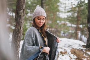 portret van jong brunette mooi vrouw in hoed en grijs poncho in de winter Woud foto